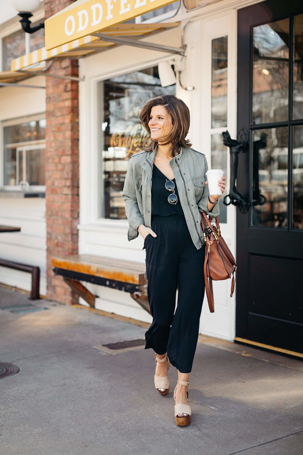 black jumpsuit paired with olive green utility jacket military jacket outfit