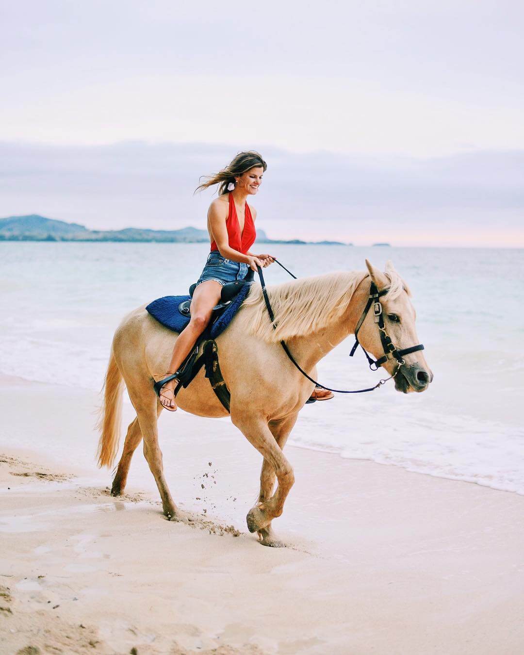 brighton keller riding horseback on the beach wearing one piece plunge neck swimsuit