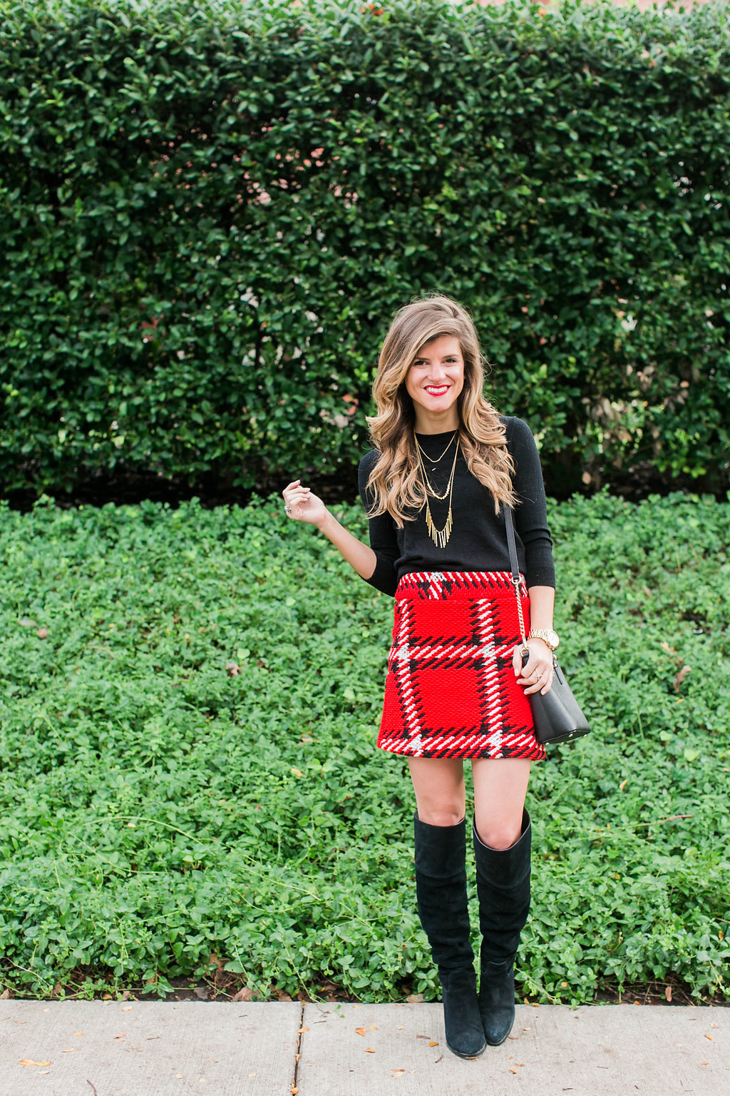 Red black plaid mini skirt with black tall boots, black sweater, gold necklace, kate spade crossbody holiday outfit 