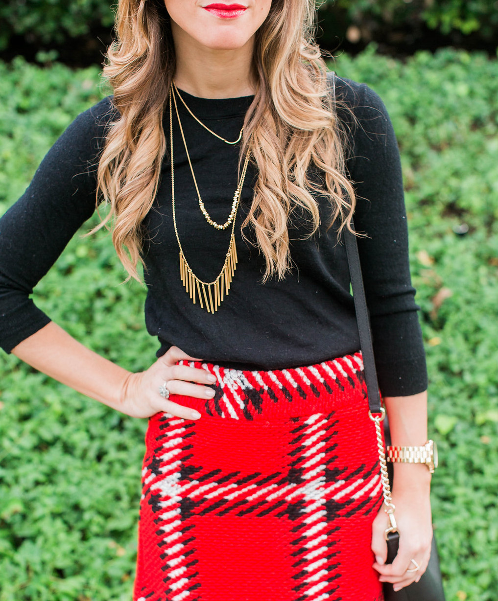 Red black plaid mini skirt with black tall boots, black sweater, gold necklace, kate spade crossbody holiday outfit 