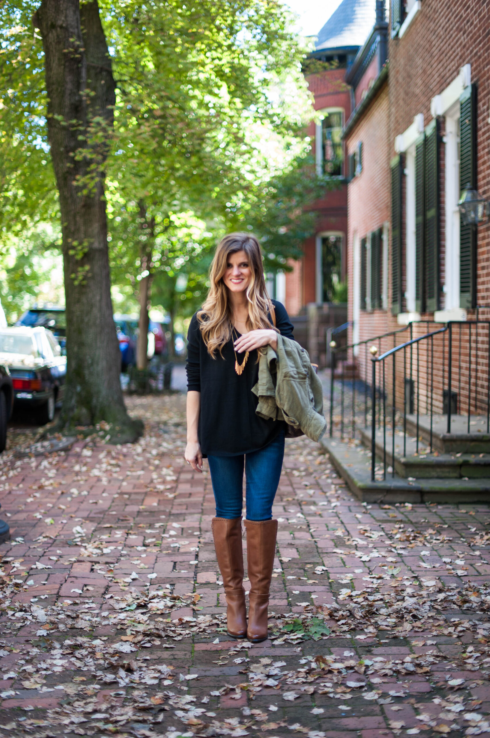 black sweater and brown boots with utility jacket and jeans