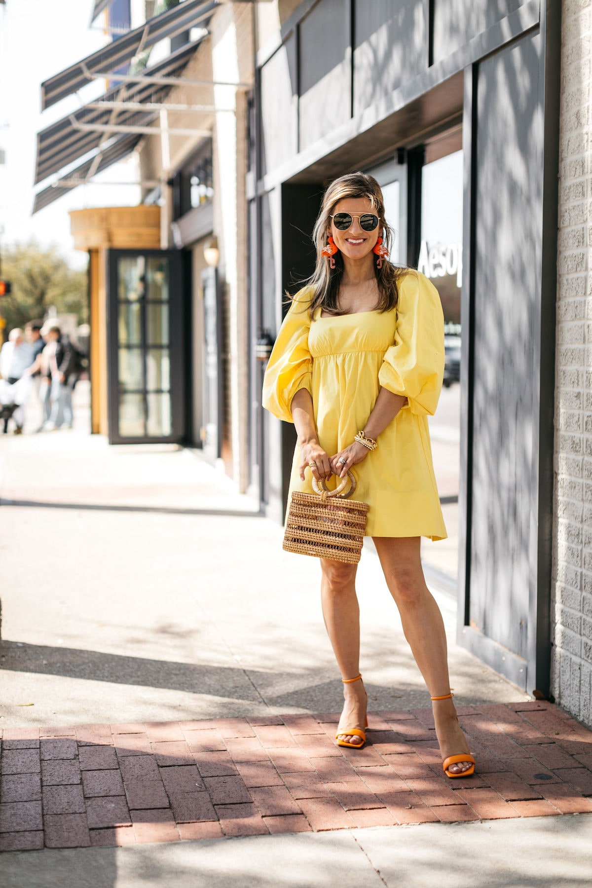 Brighton Butler wearing staud yellow dress with flamingo earrings and cult gaia bag