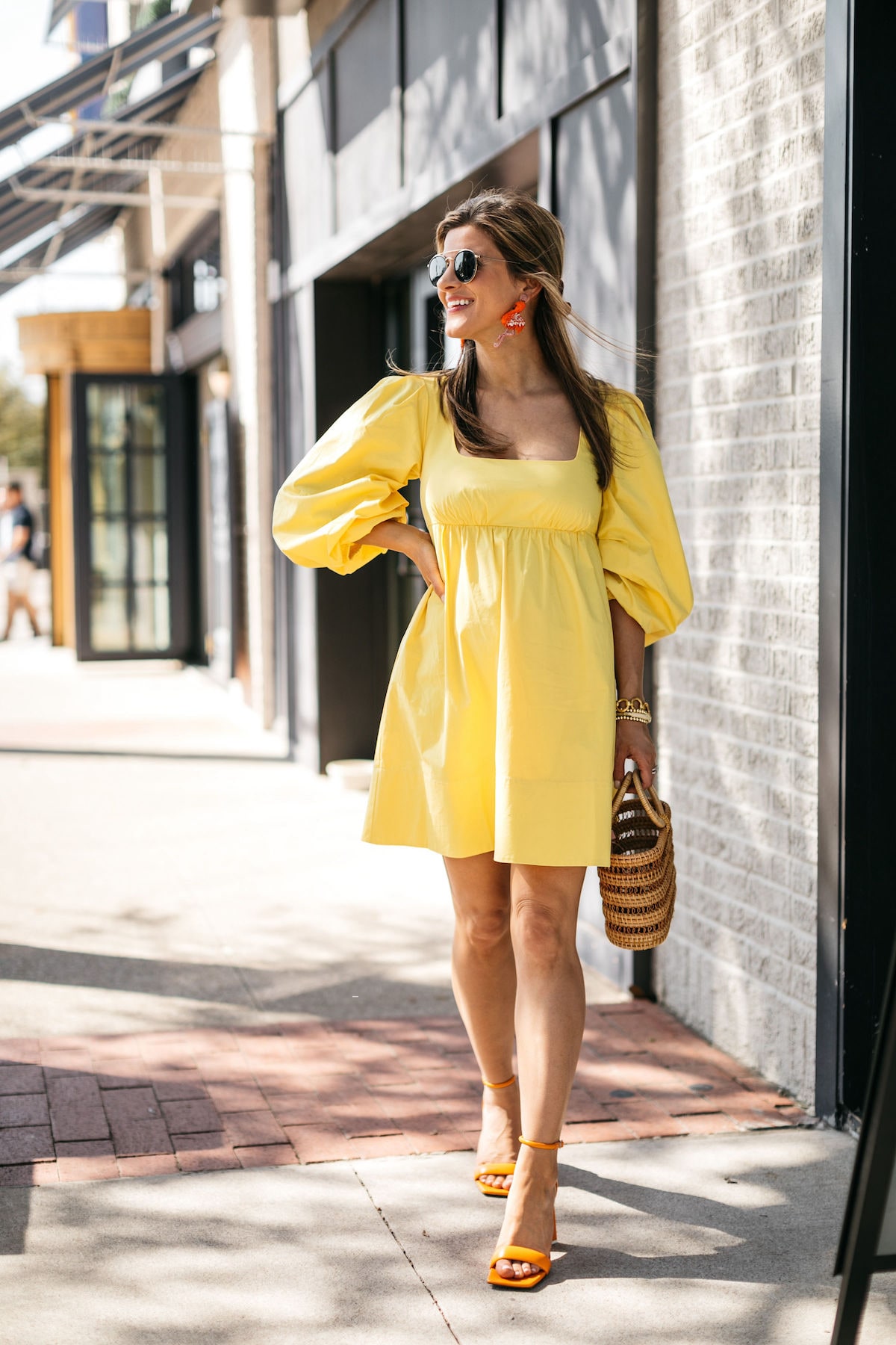 Brighton Butler wearing staud yellow dress with flamingo earrings and cult gaia bag