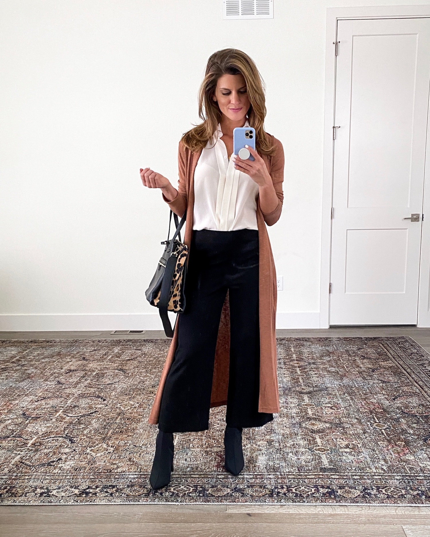 Brighton Keller wearing black work pants, white collar top, duster and black booties