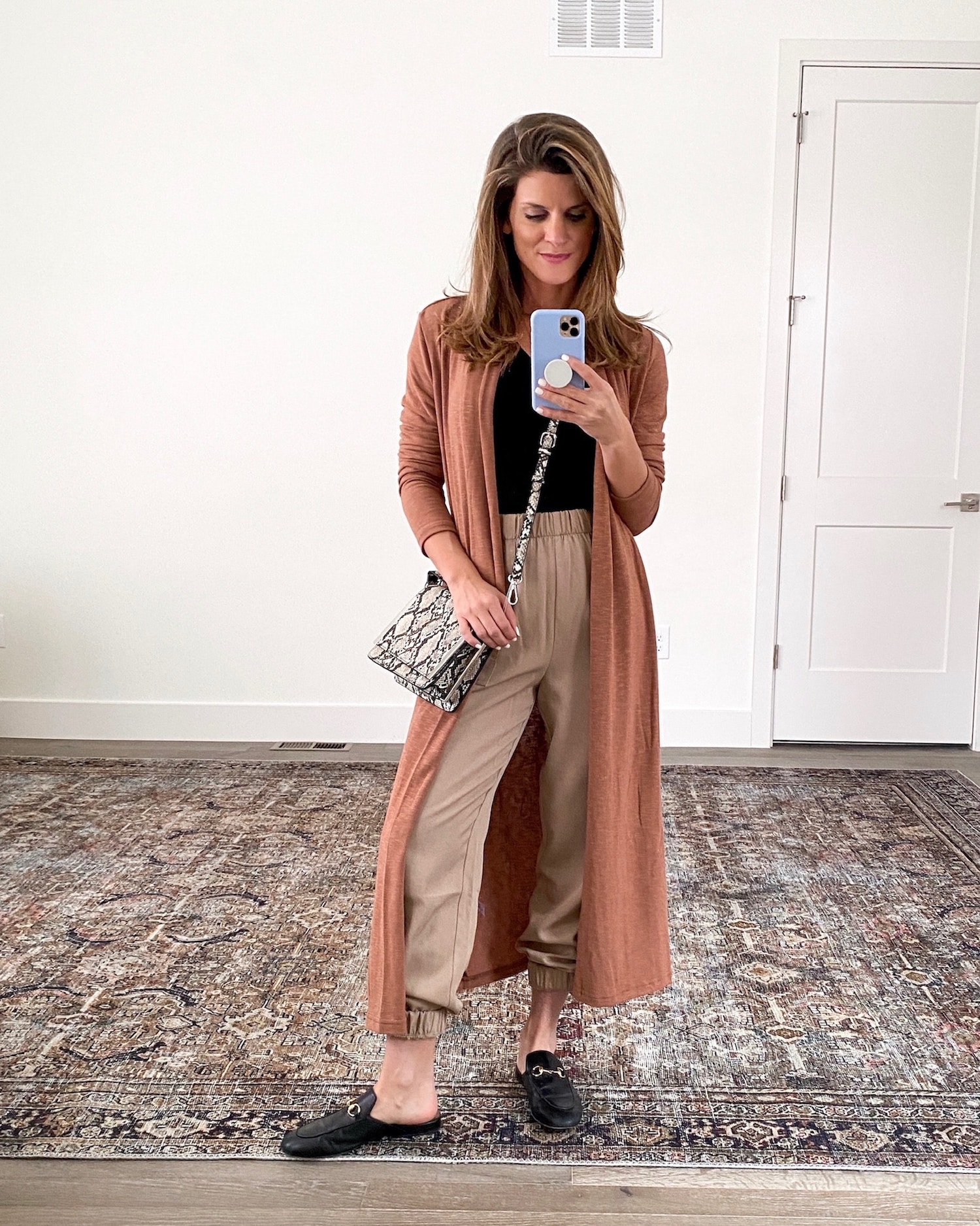 Brighton Keller wearing black shirt, duster, Gucci flats, tan joggers and python purse