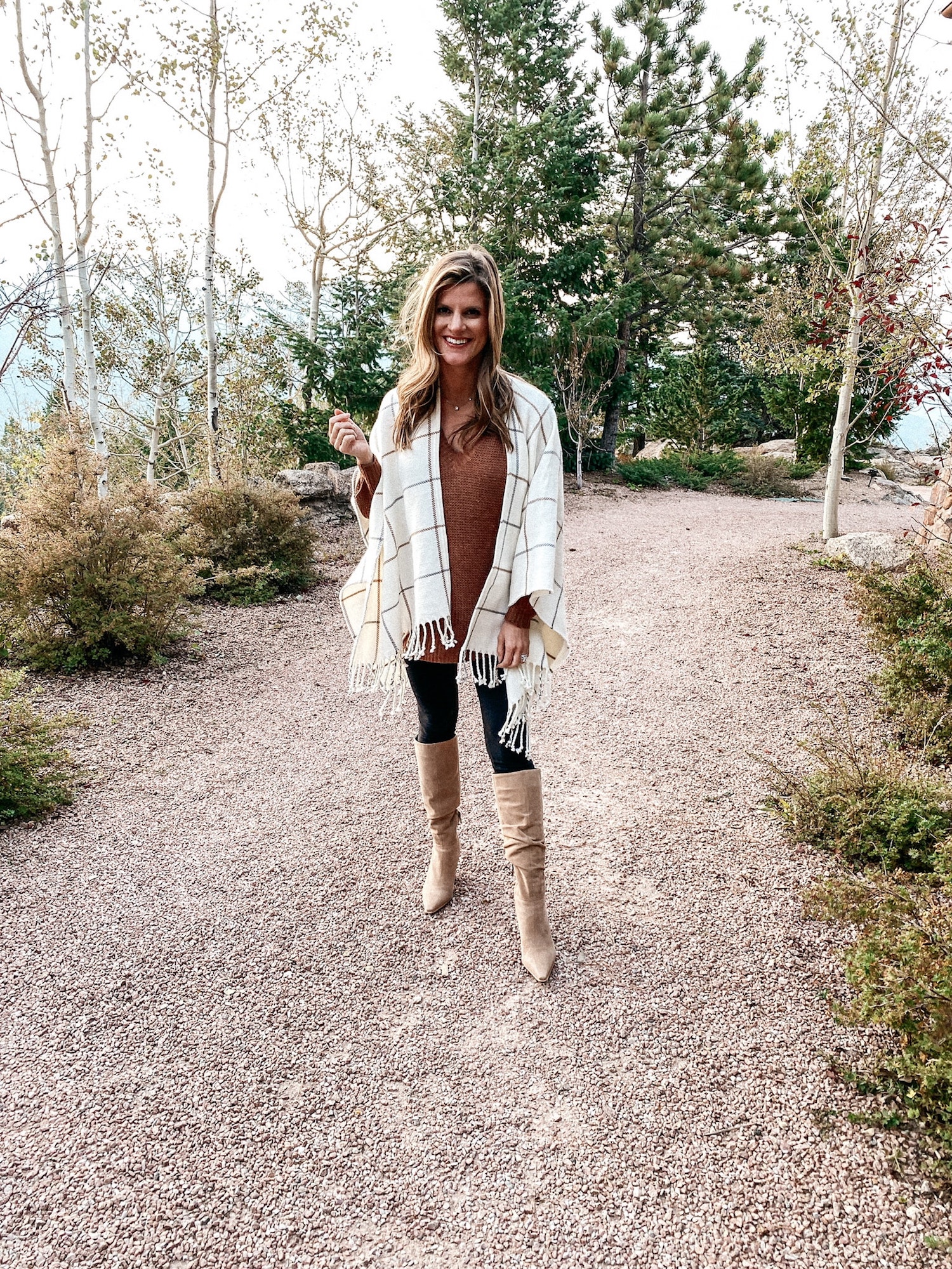 Brighton Butler wearing a brown sweater, black leggings, tan knee-high boots and windowpane scarf