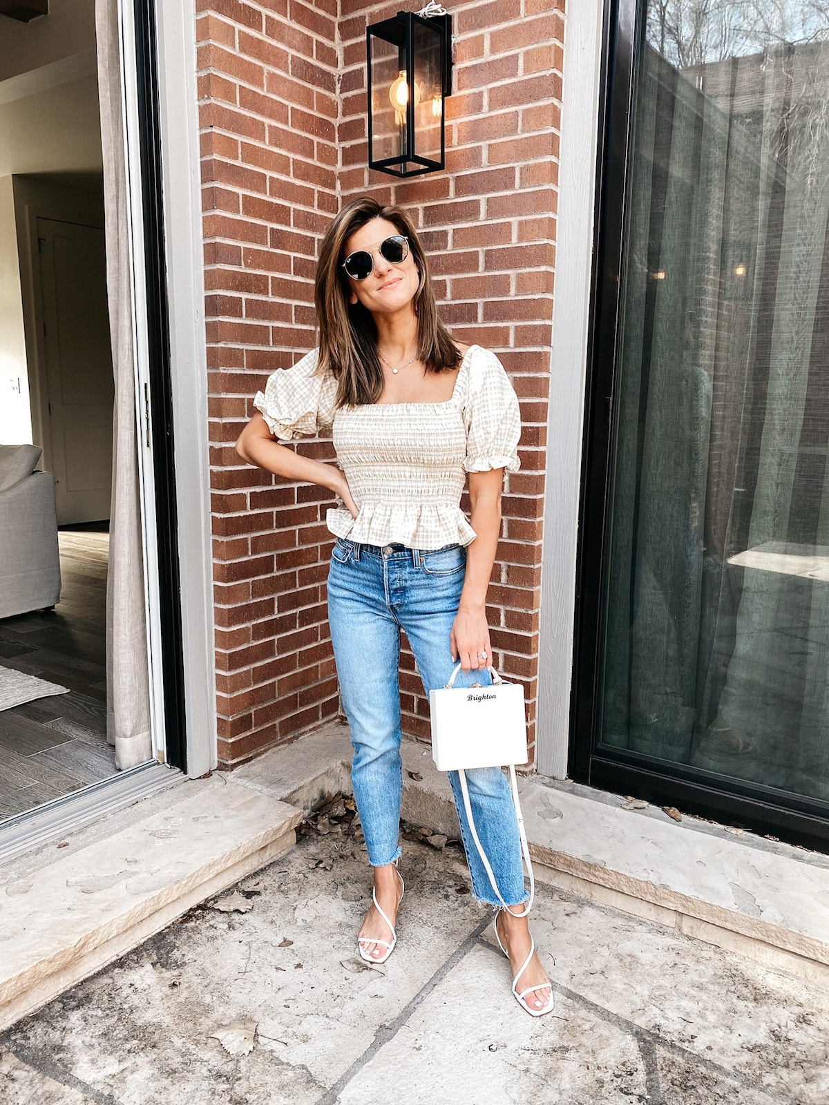 Brighton Keller wearing smocked tan top, Levi jeans, scrappy sandals and white purse