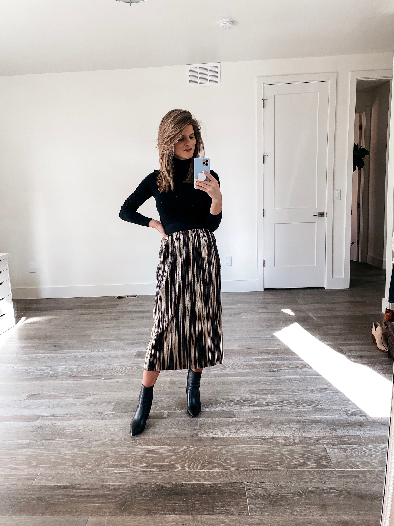 brighton keller wearing black turtleneck sweater and metallic skirt with black leather booties