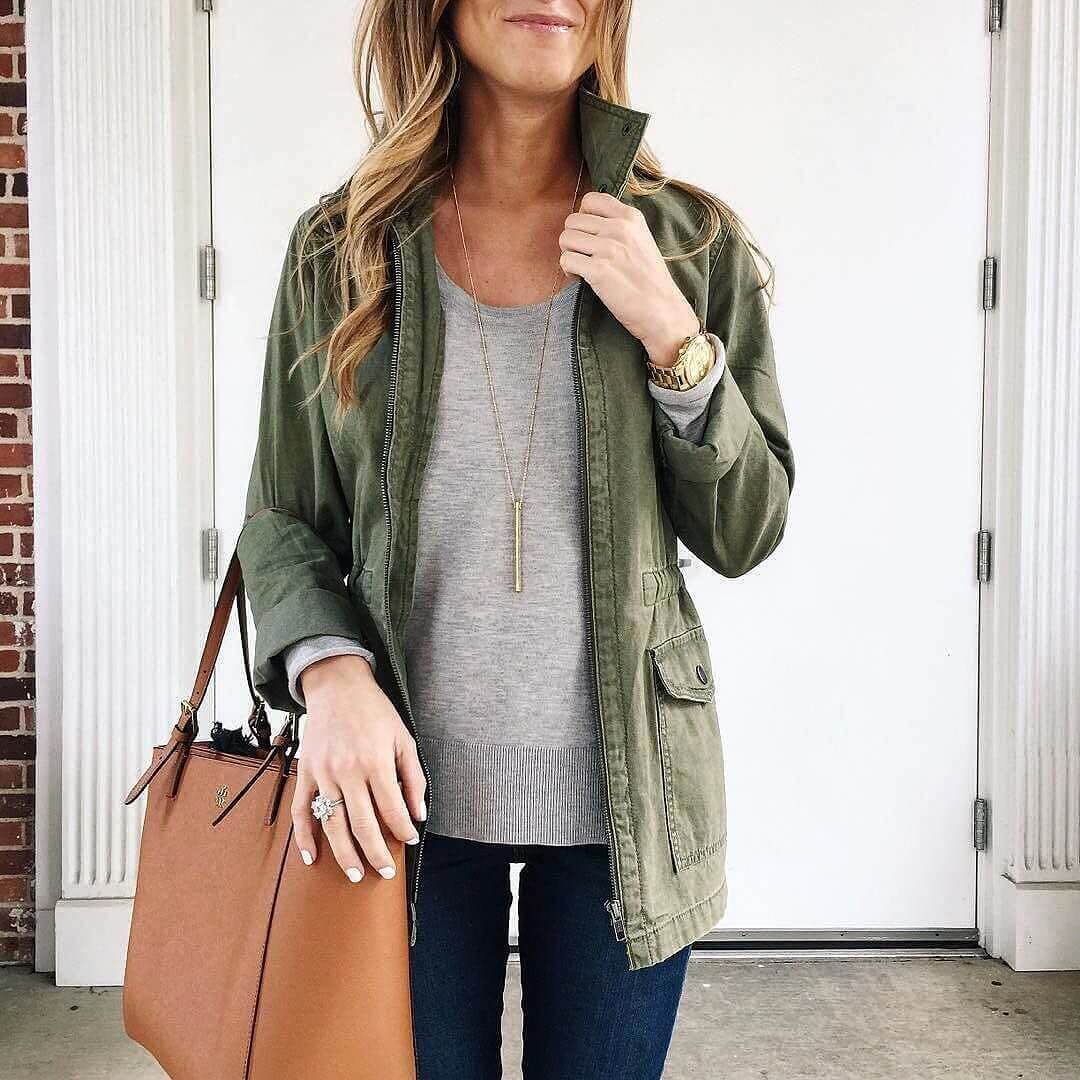 close up of utility jacket and grey sweater with tory burch tote