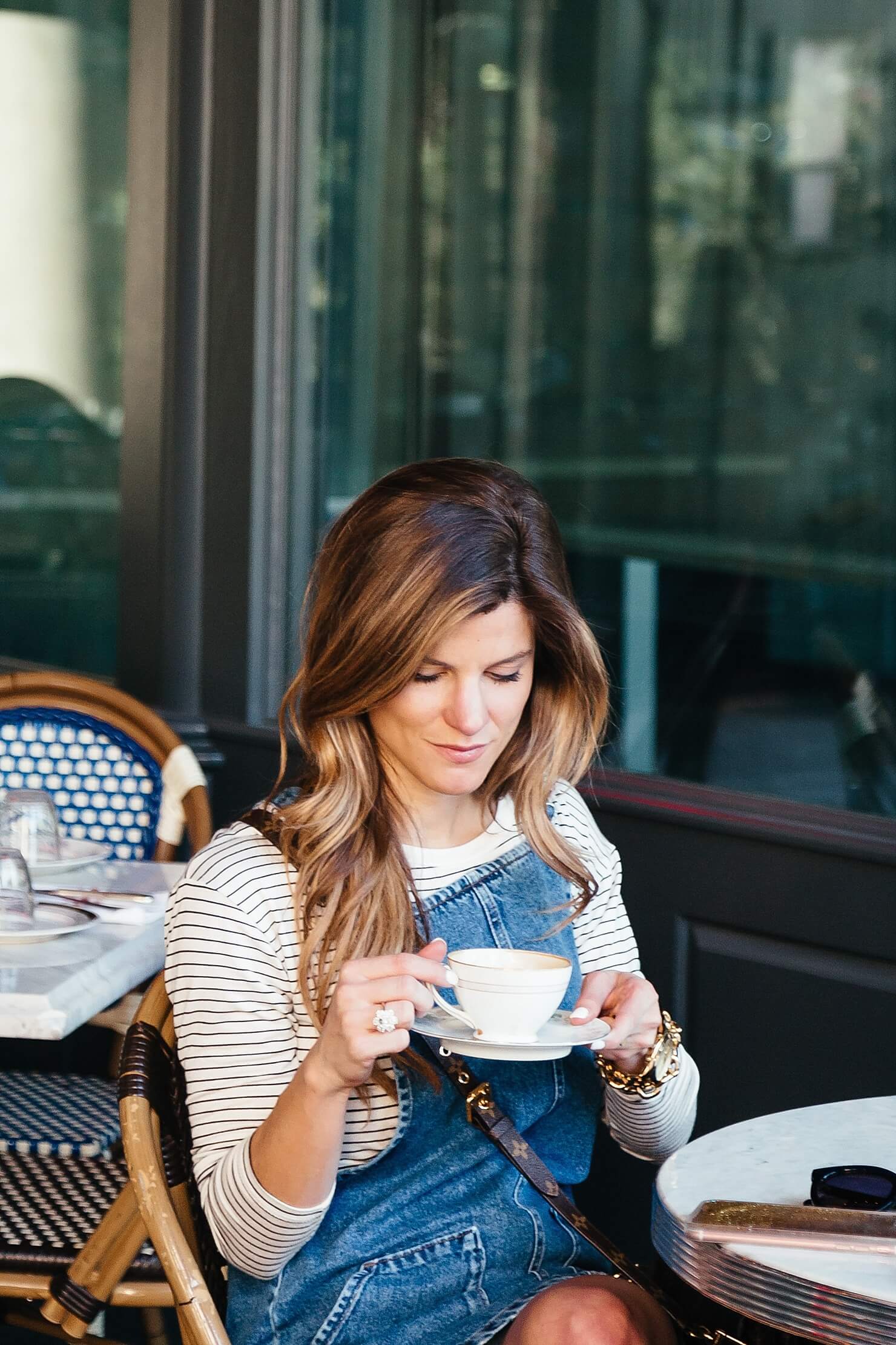 denim overalls layered over black and white striped long sleeve tee vince sneakers 