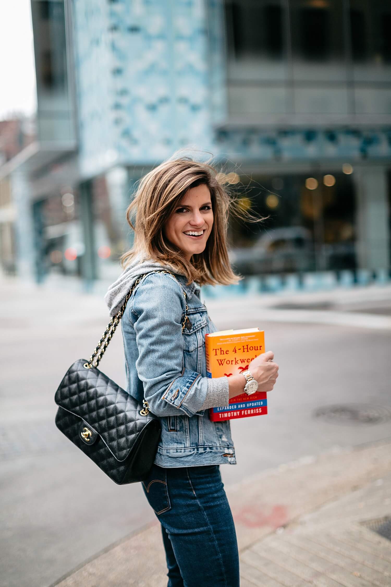 brighton keller wearing denim jacket and jeans holding four hour work week