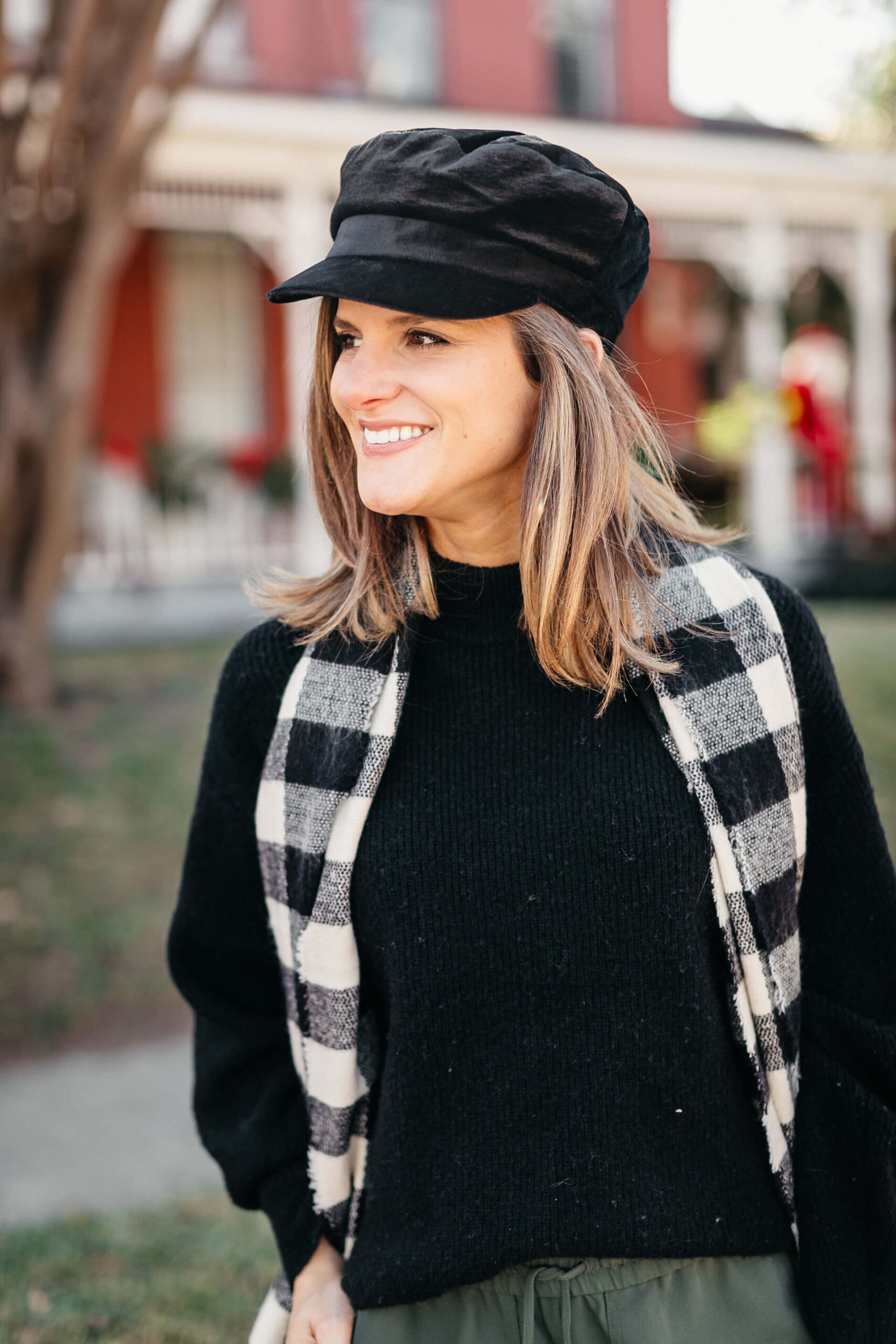 green joggers, black sweater, checkered scarf and cap