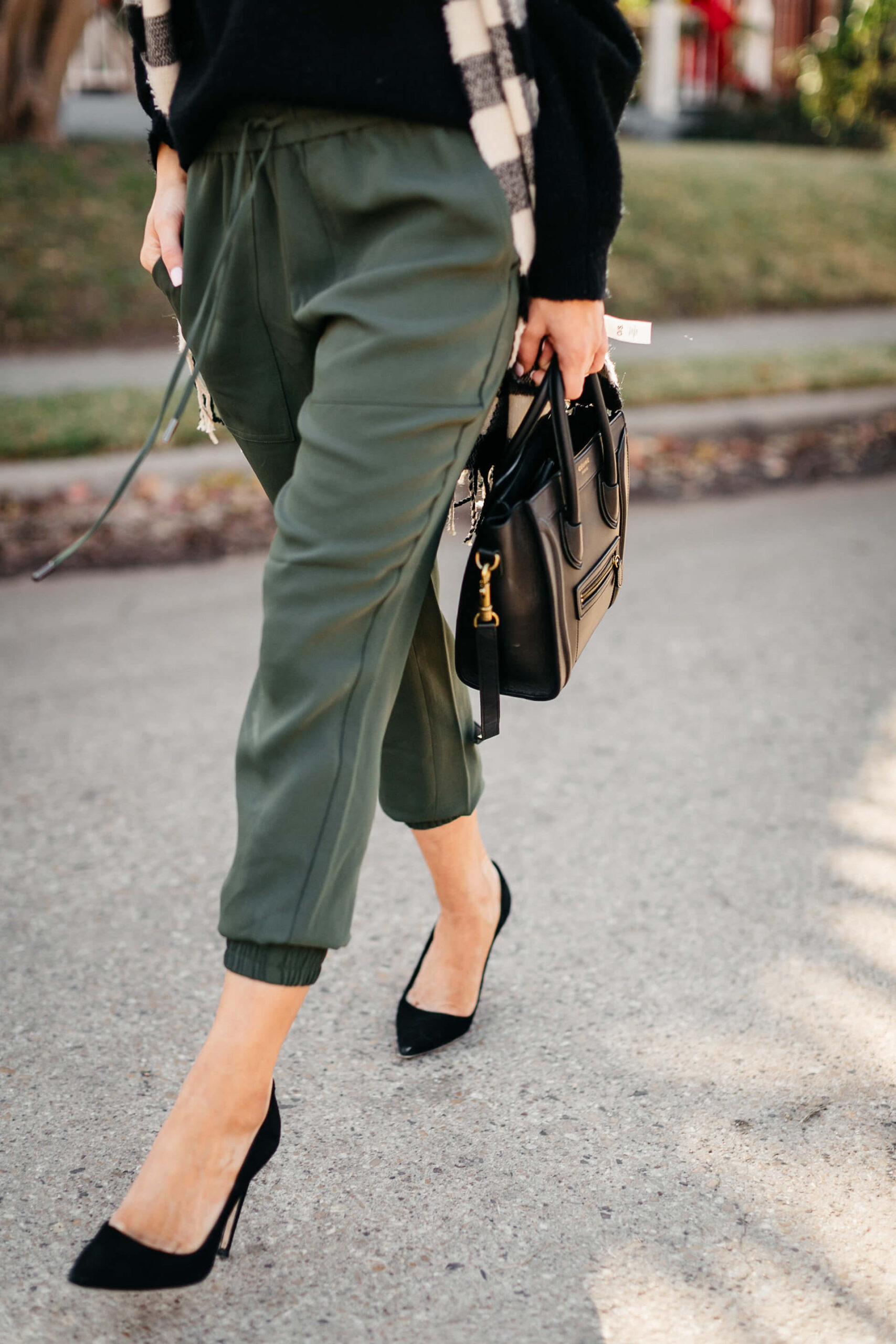 green joggers, black sweater, checkered scarf and cap