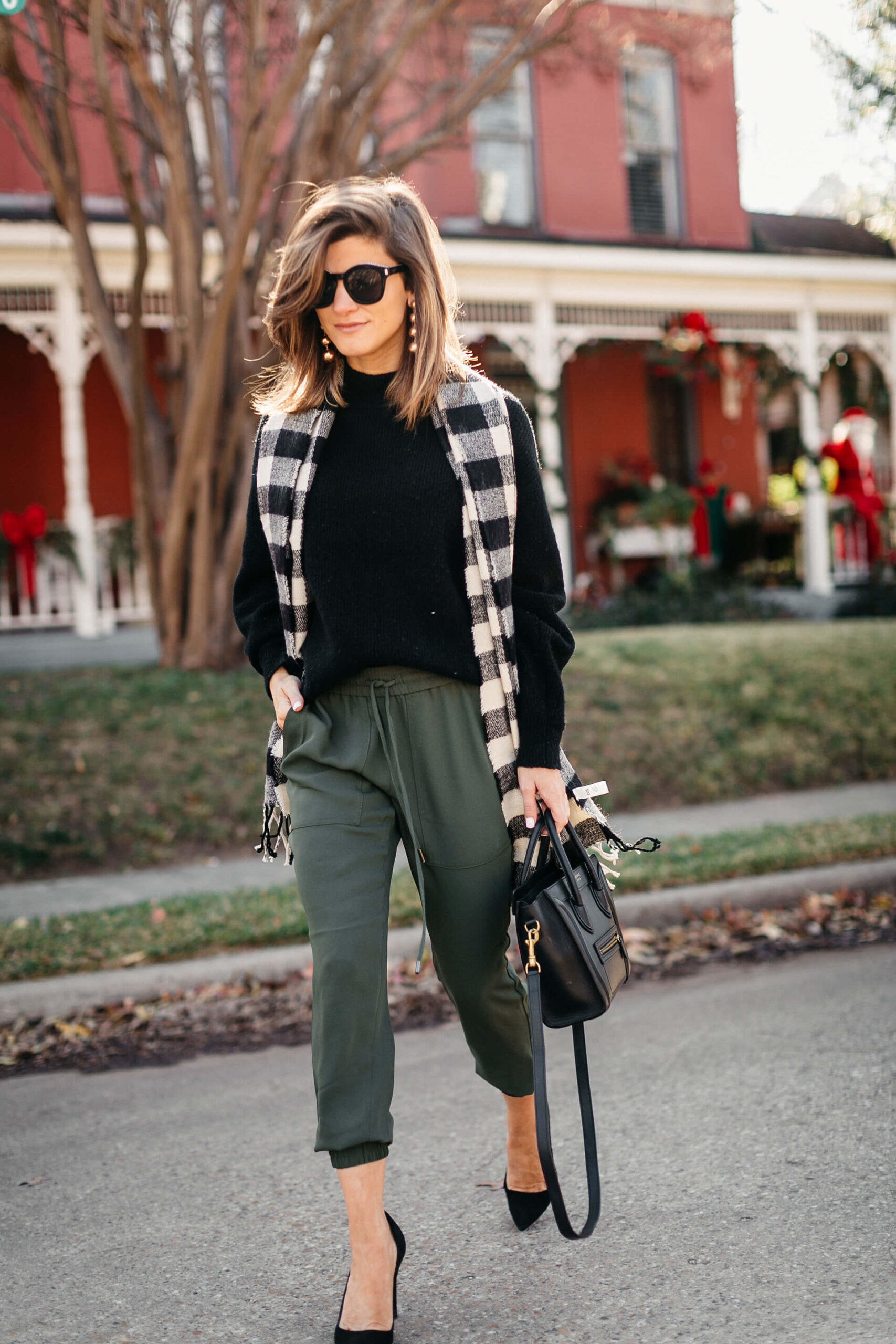 green joggers, black sweater, checkered scarf and cap