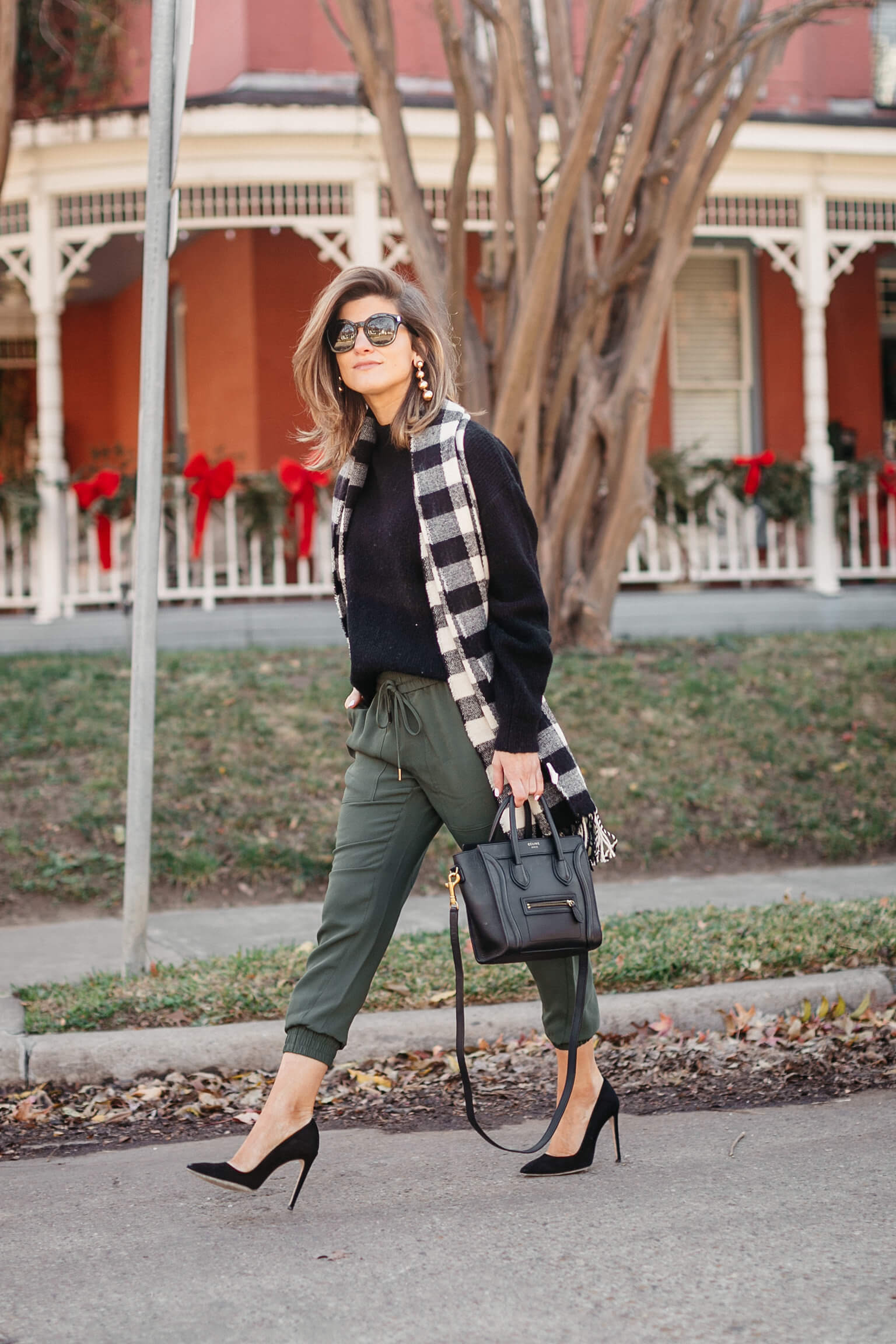 green joggers, black sweater, checkered scarf and cap