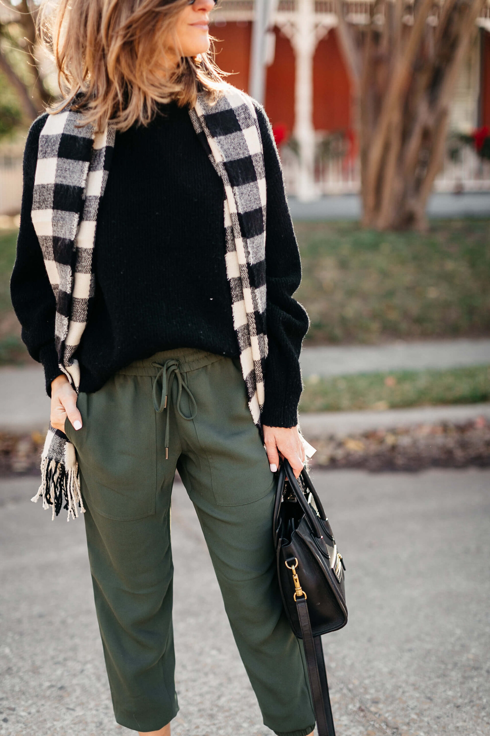 green joggers, black sweater, checkered scarf and cap