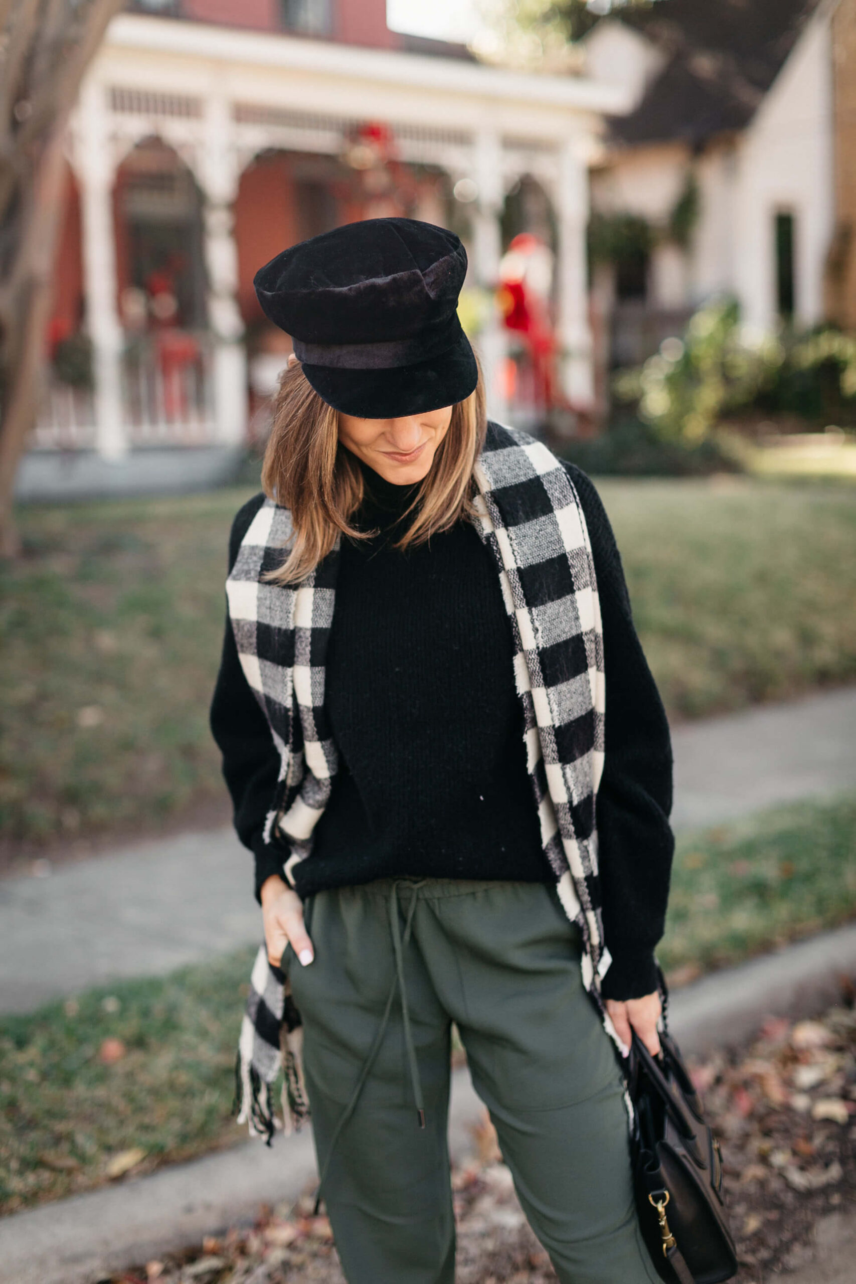 green joggers, black sweater, checkered scarf and cap