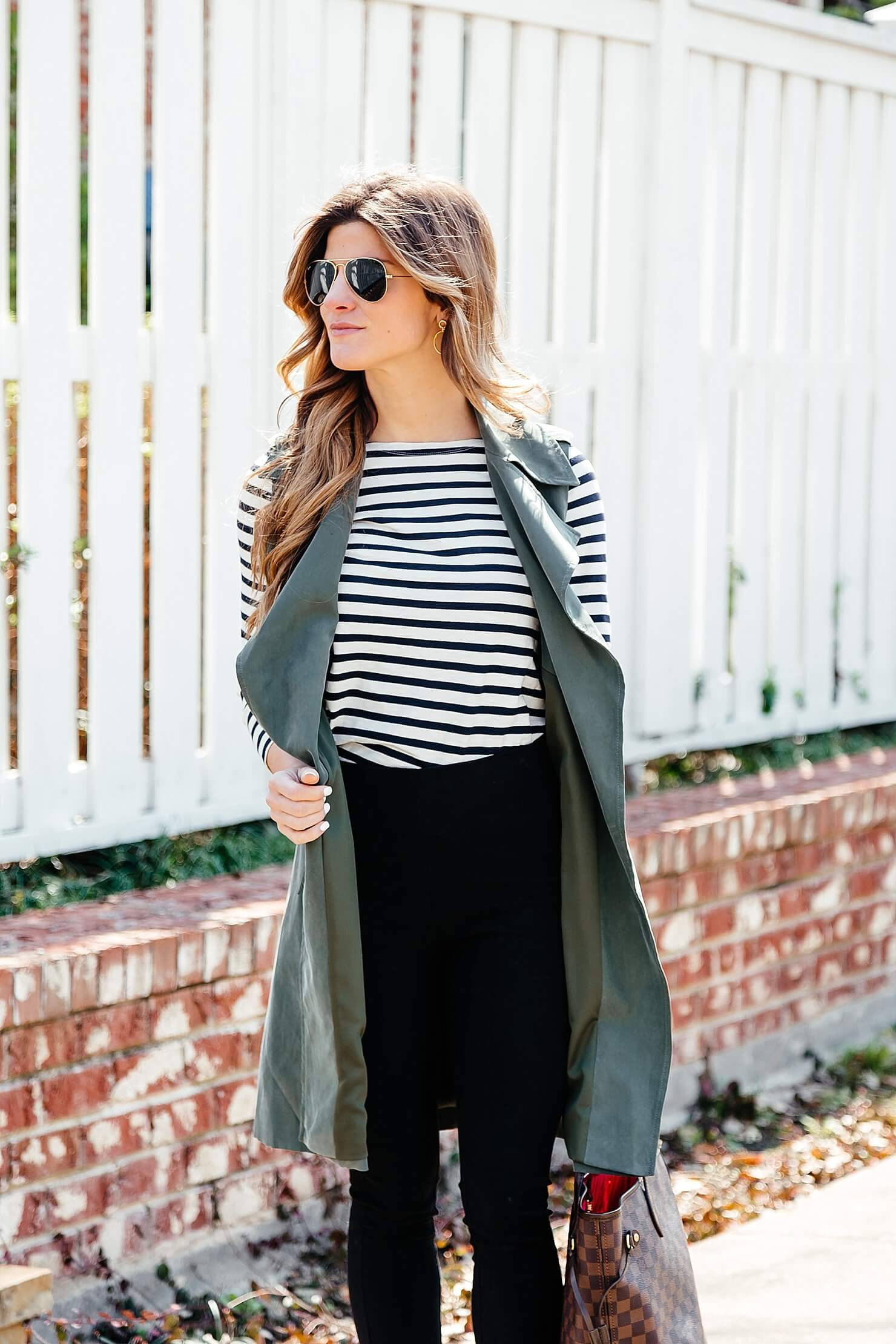 green trench vest, striped tee, black pants, business casual outfit idea, longline sleeveless jacket, black work pants outfit