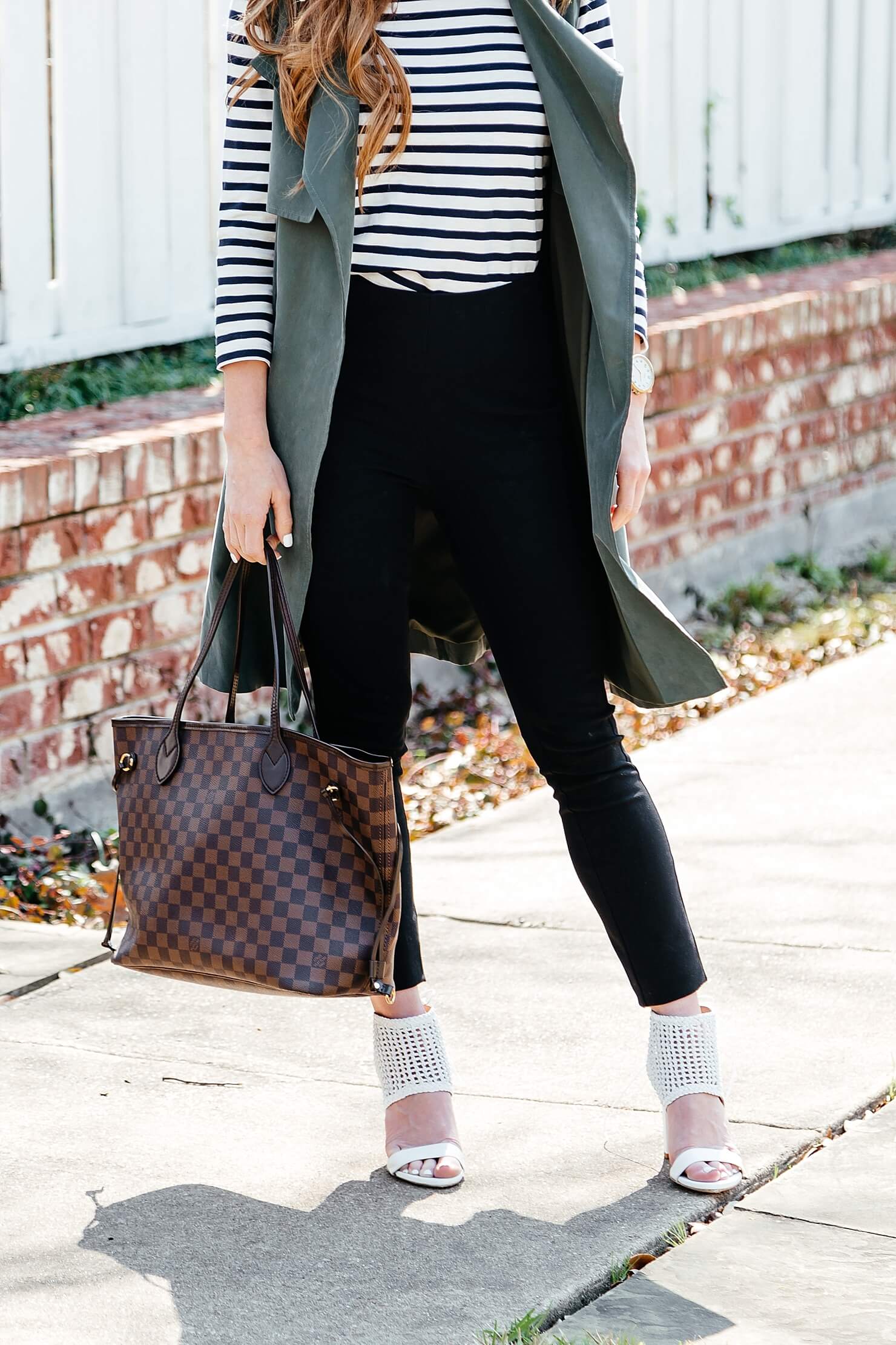 green trench vest, striped tee, black pants, business casual outfit idea, longline sleeveless jacket, black work pants outfit