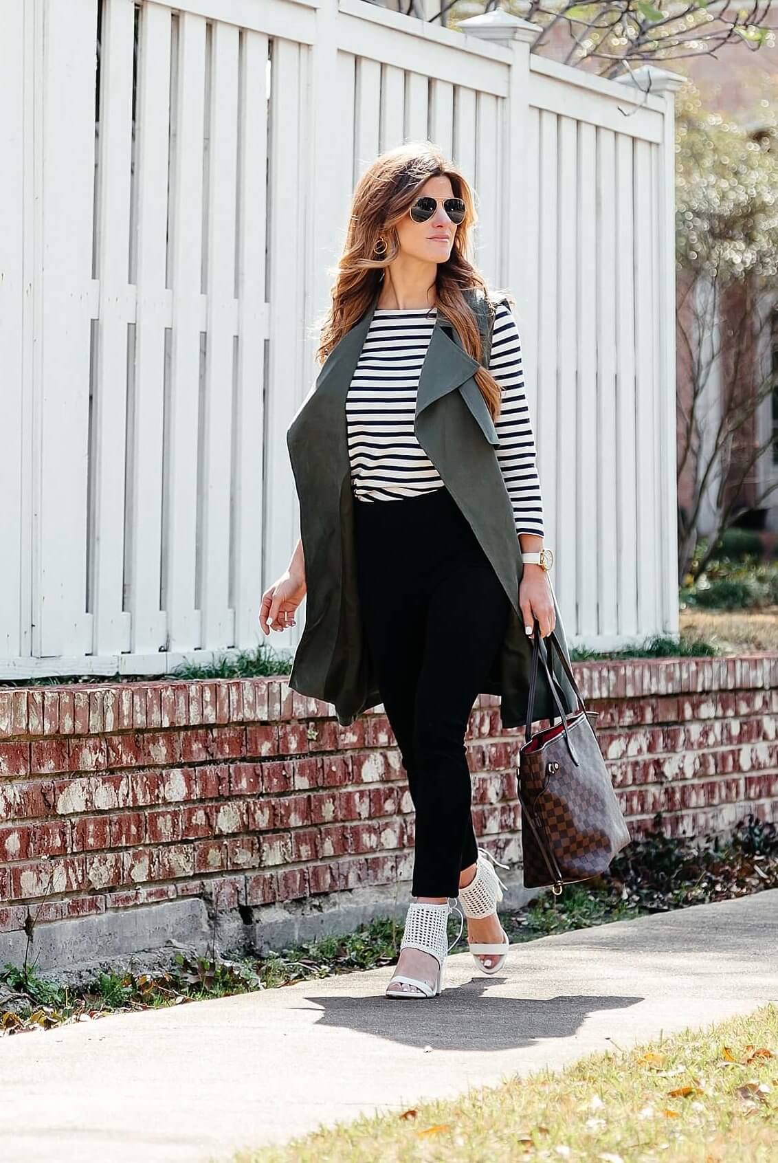 green trench vest, striped tee, black pants, business casual outfit idea, longline sleeveless jacket, black work pants outfit