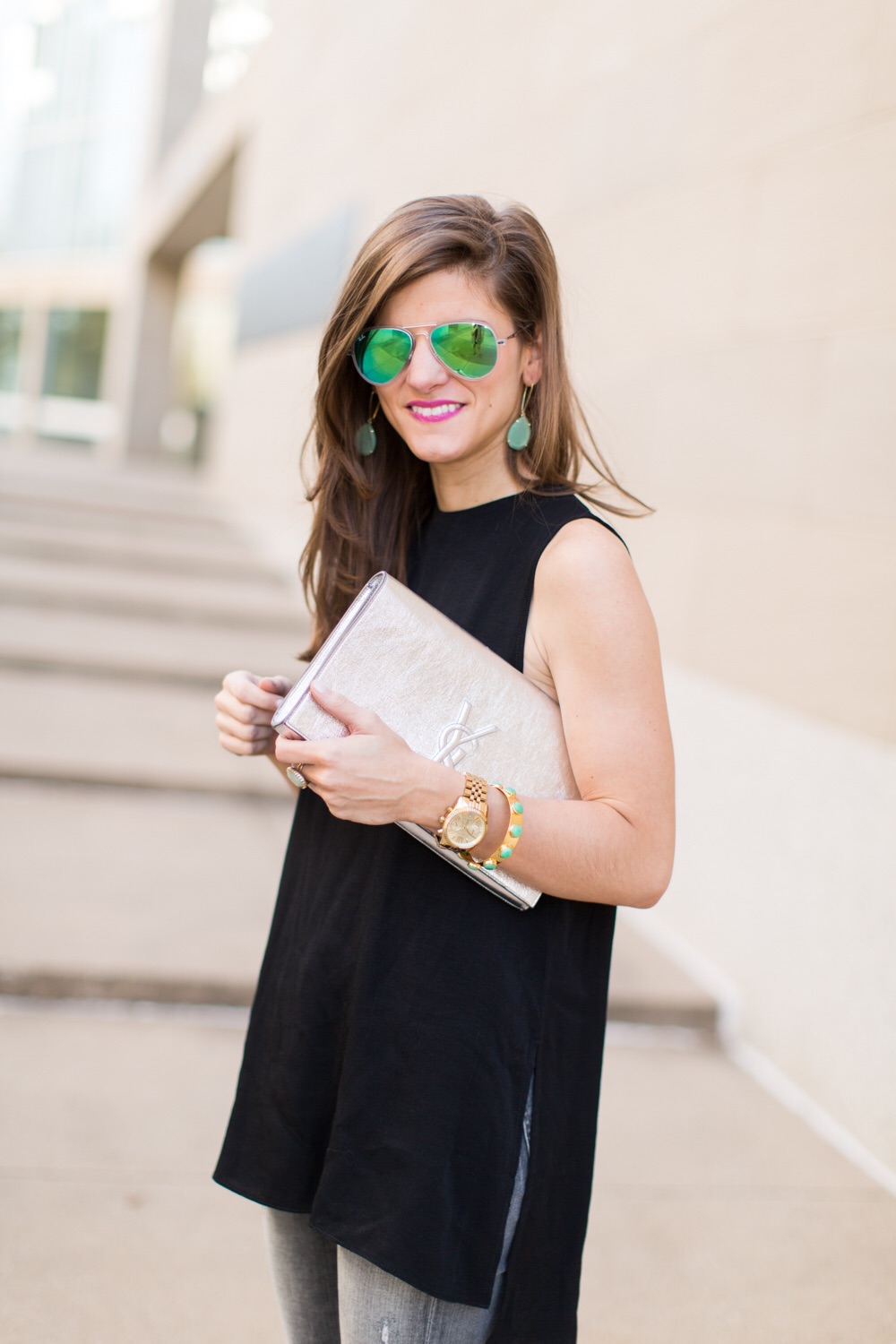 silver ysl logo clutch, green mirrored aviators, kendra scott earrings, black sleeveless tunic, gold watch