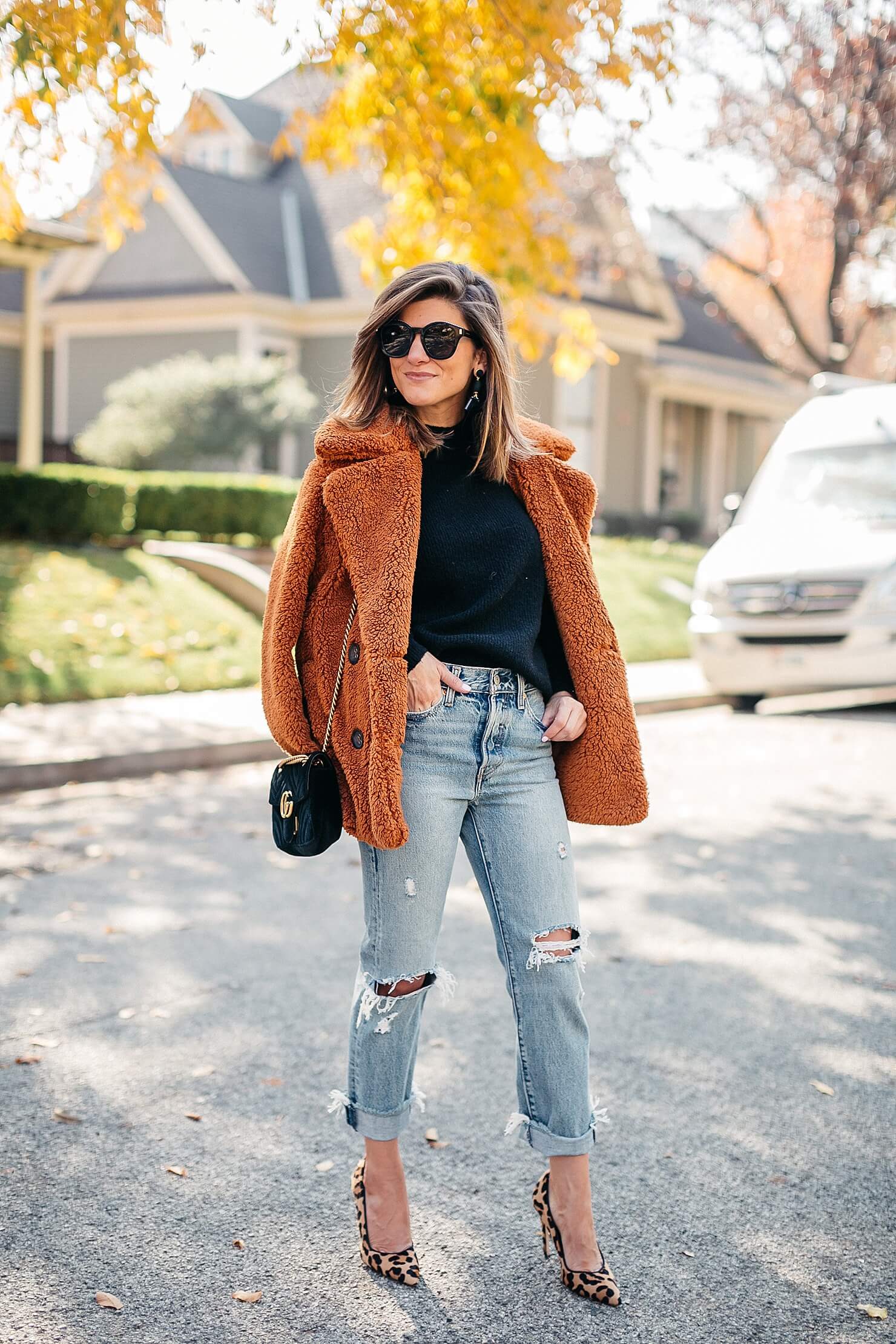 orange teddy coat, black sweater, distressed levi jeans, leopard pumps and gucci cross body 