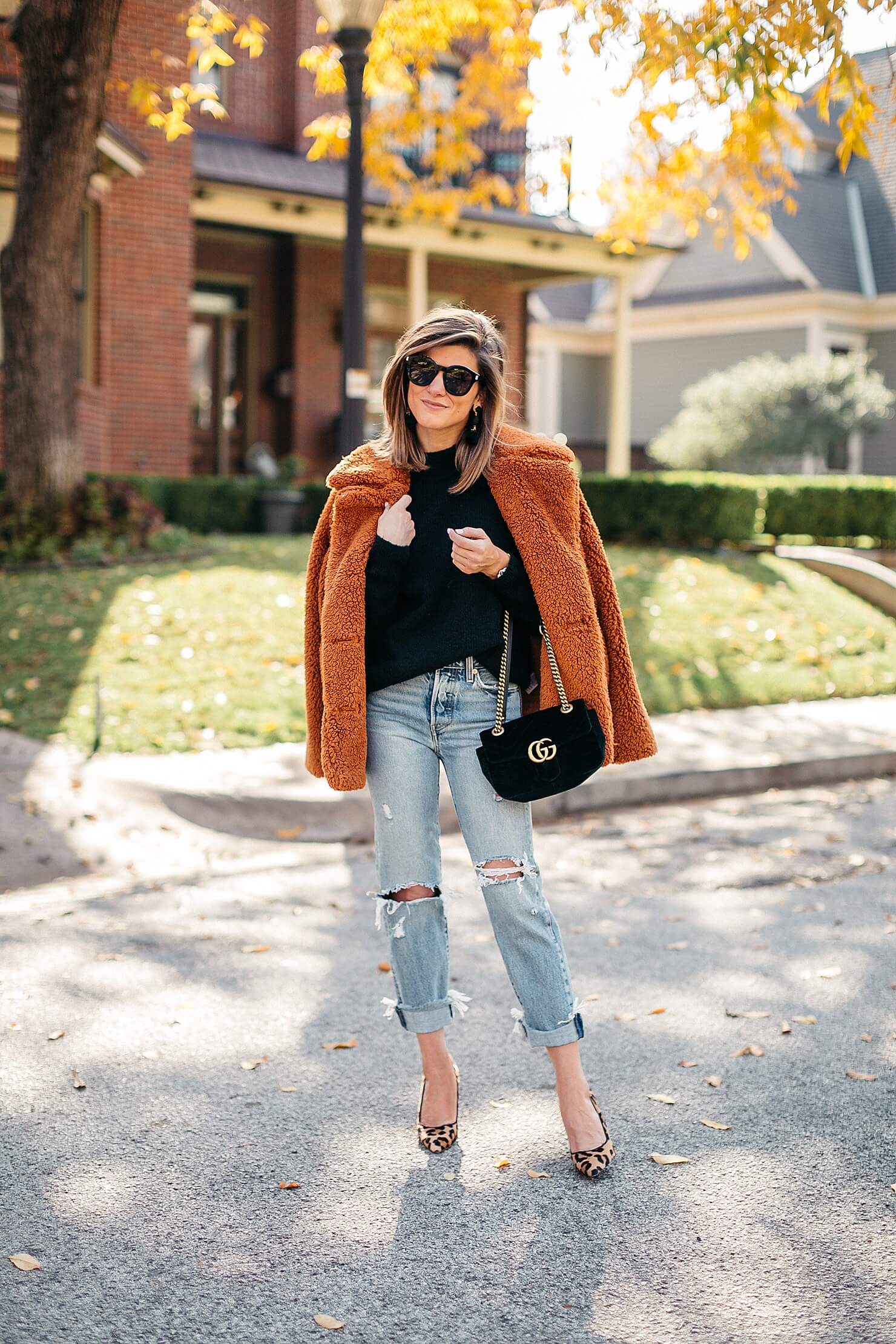 orange teddy coat, black sweater, distressed levi jeans, leopard pumps and gucci cross body 