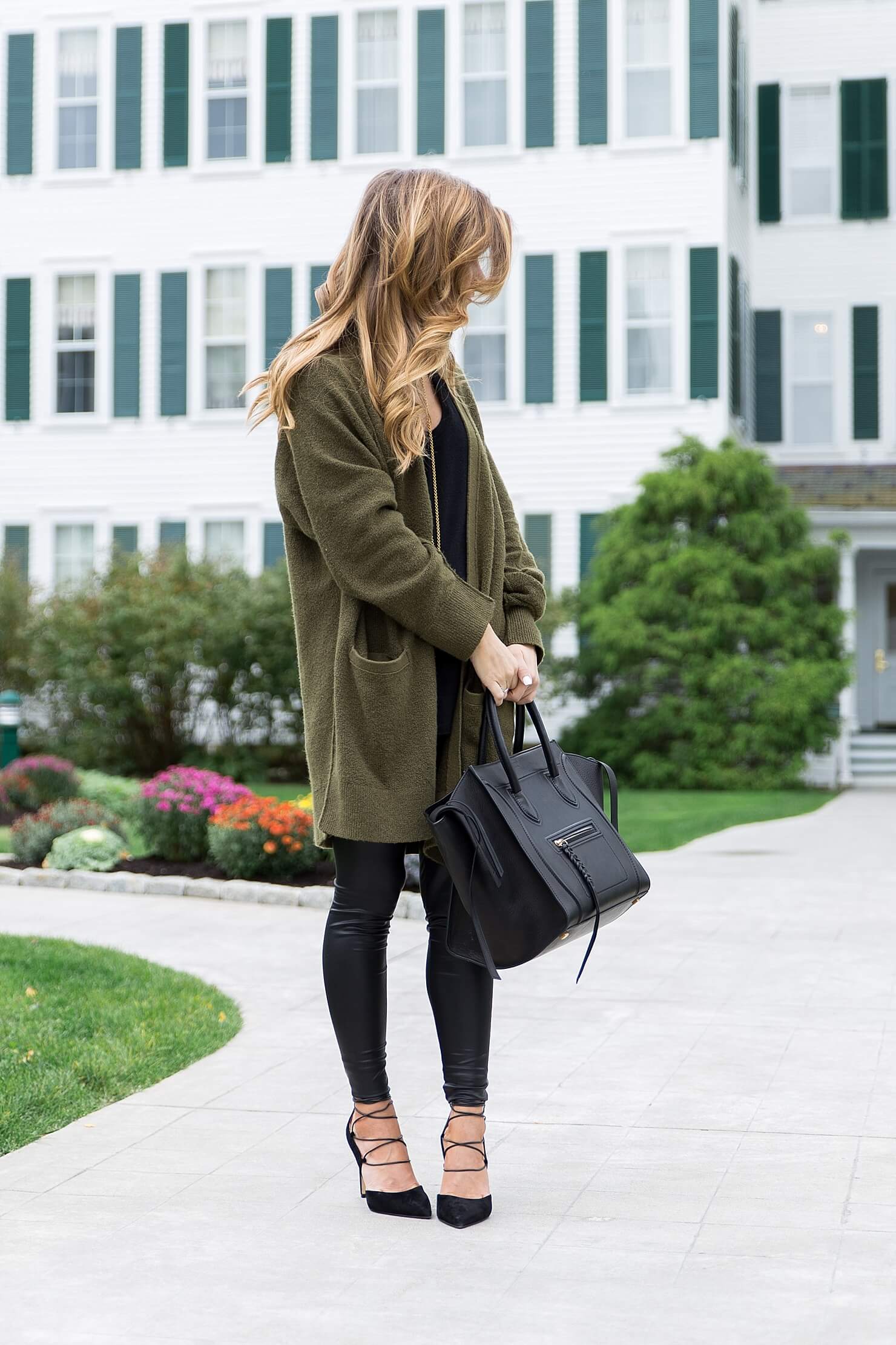 all black outfit idea, wearing all black with a long olive cardigan, liquid leather leggings winter outfit, black on black outfit, going out winter outfit, winter date night outfit, celine phantom tote, sam edelman strappy heels, winter all black outfit