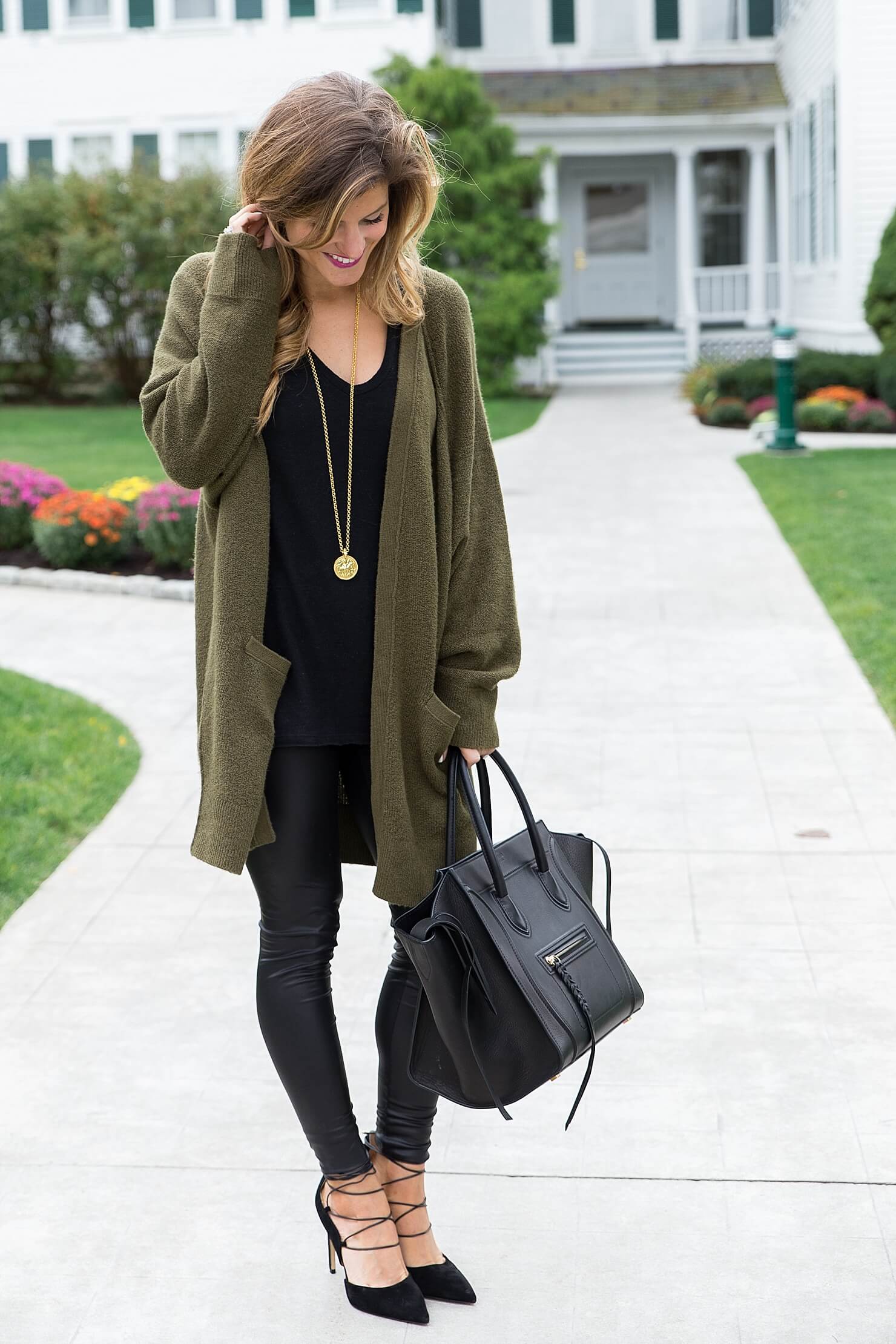 all black outfit idea, wearing all black with a long olive cardigan, liquid leather leggings winter outfit, black on black outfit, going out winter outfit, winter date night outfit, celine phantom tote, sam edelman strappy heels, winter all black outfit