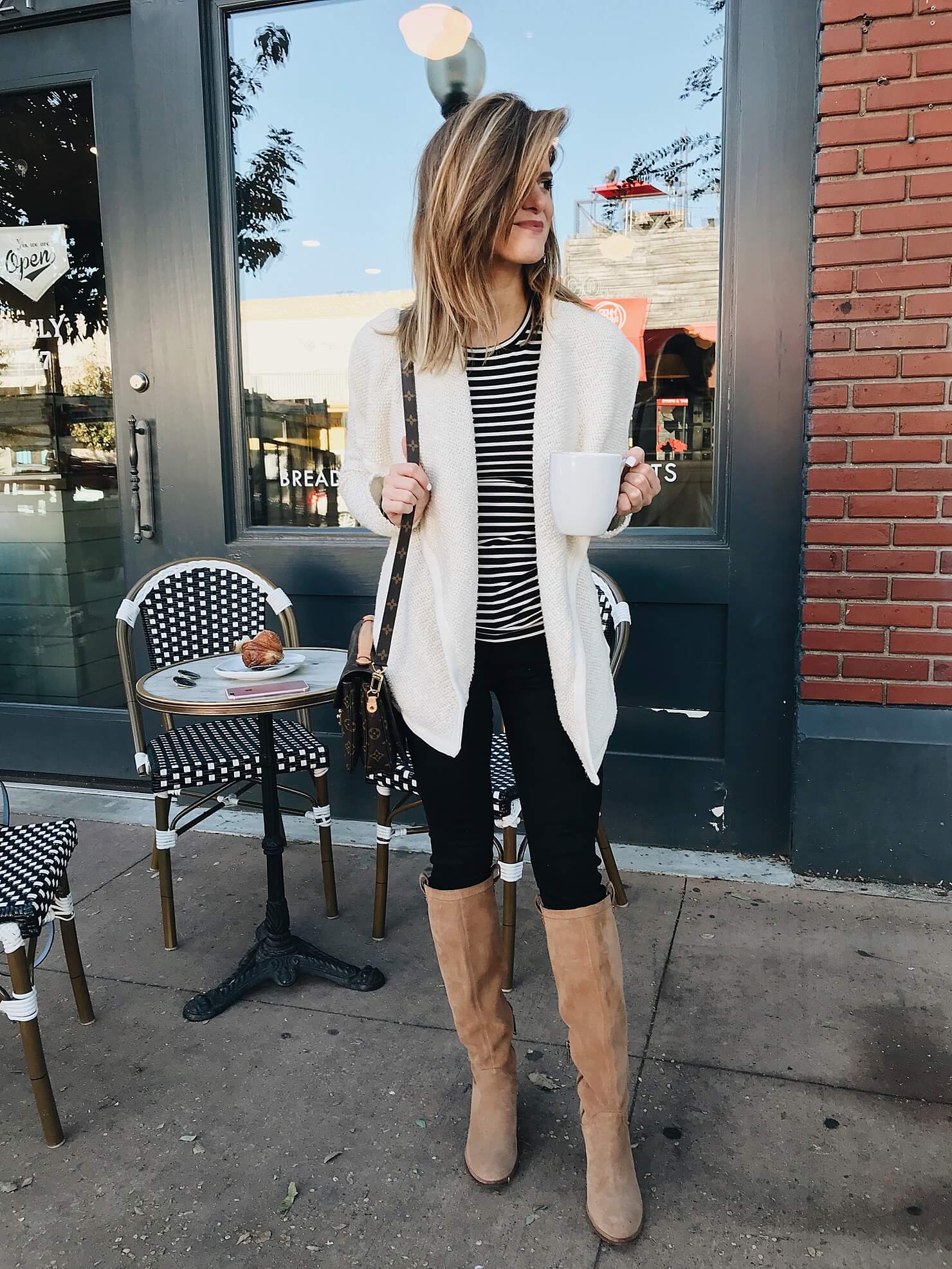 fall outfit idea with drape open front jacket, black and white stripe crewneck tee, black jeans, tall cognac suede boots