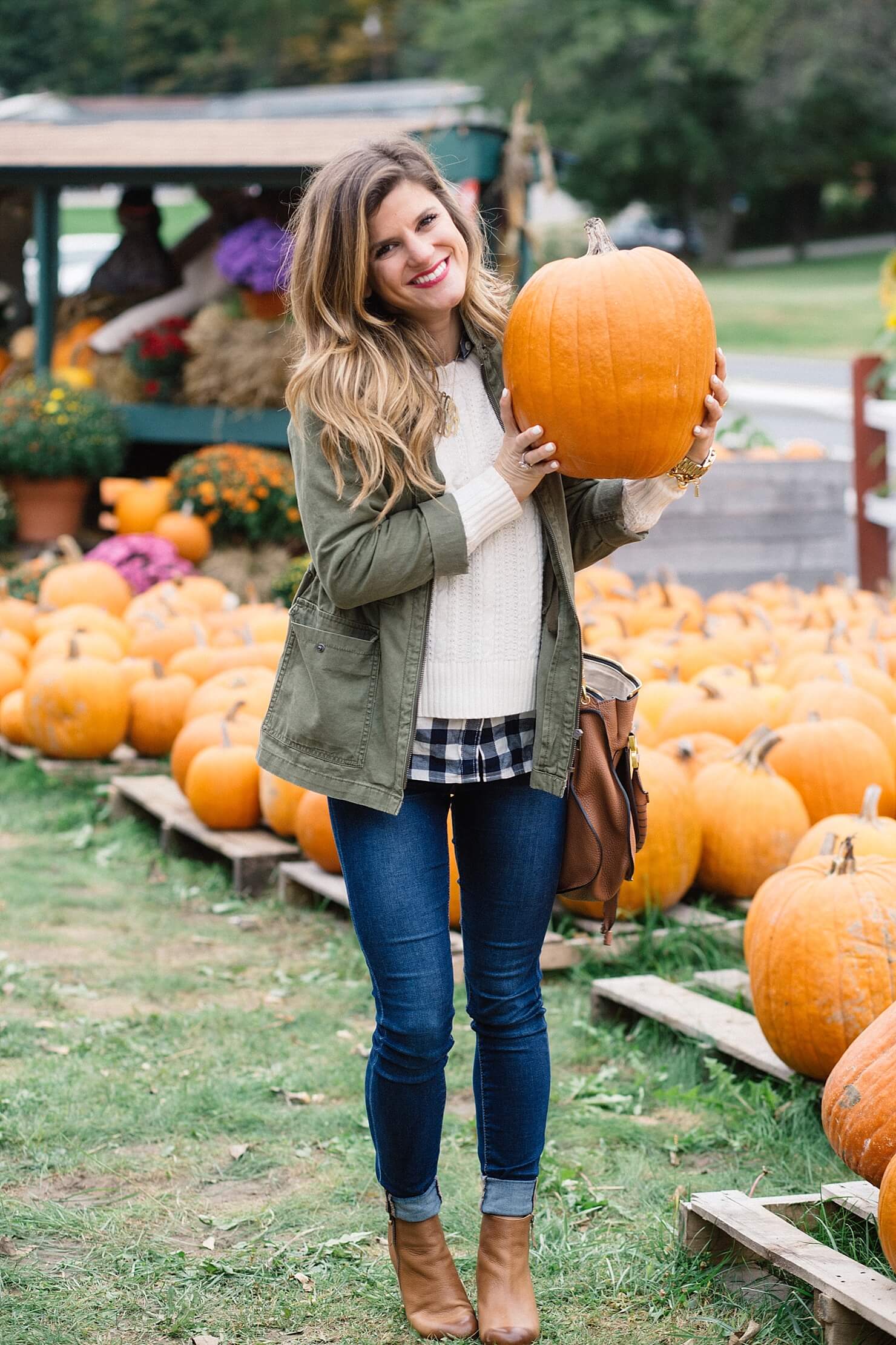 fall outfit, olive green military jacket, cable knit sweater with gingham shirt underneath, layered sweater and gingham button up shirt, rolled up jeans and booties, jeans and booties, utility jacket outfit, cognac ankle booties, monogram necklace, chloe ran bag, cute fall casual outfit