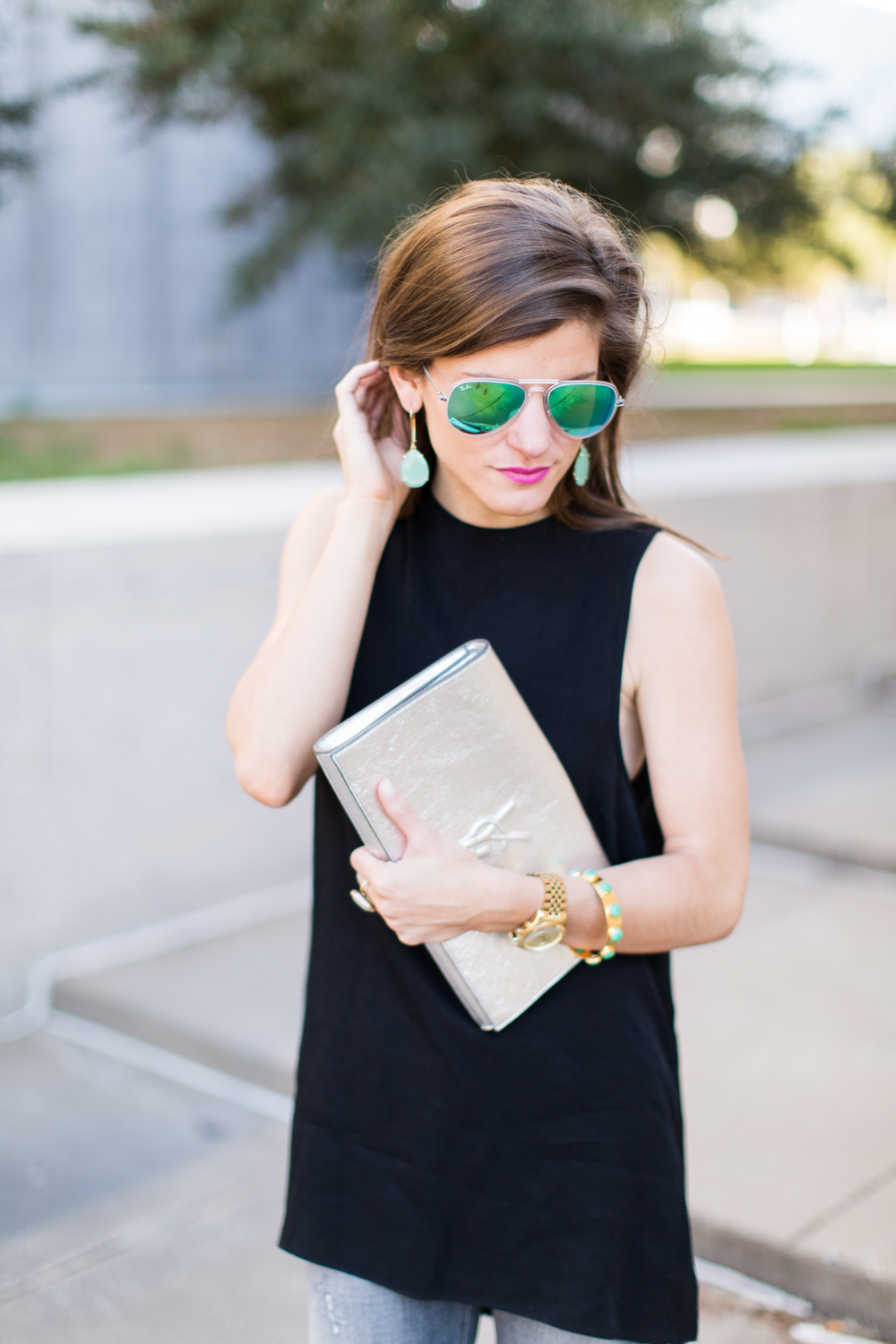 silver ysl logo clutch, green mirrored aviators, kendra scott earrings, black sleeveless tunic, gold watch